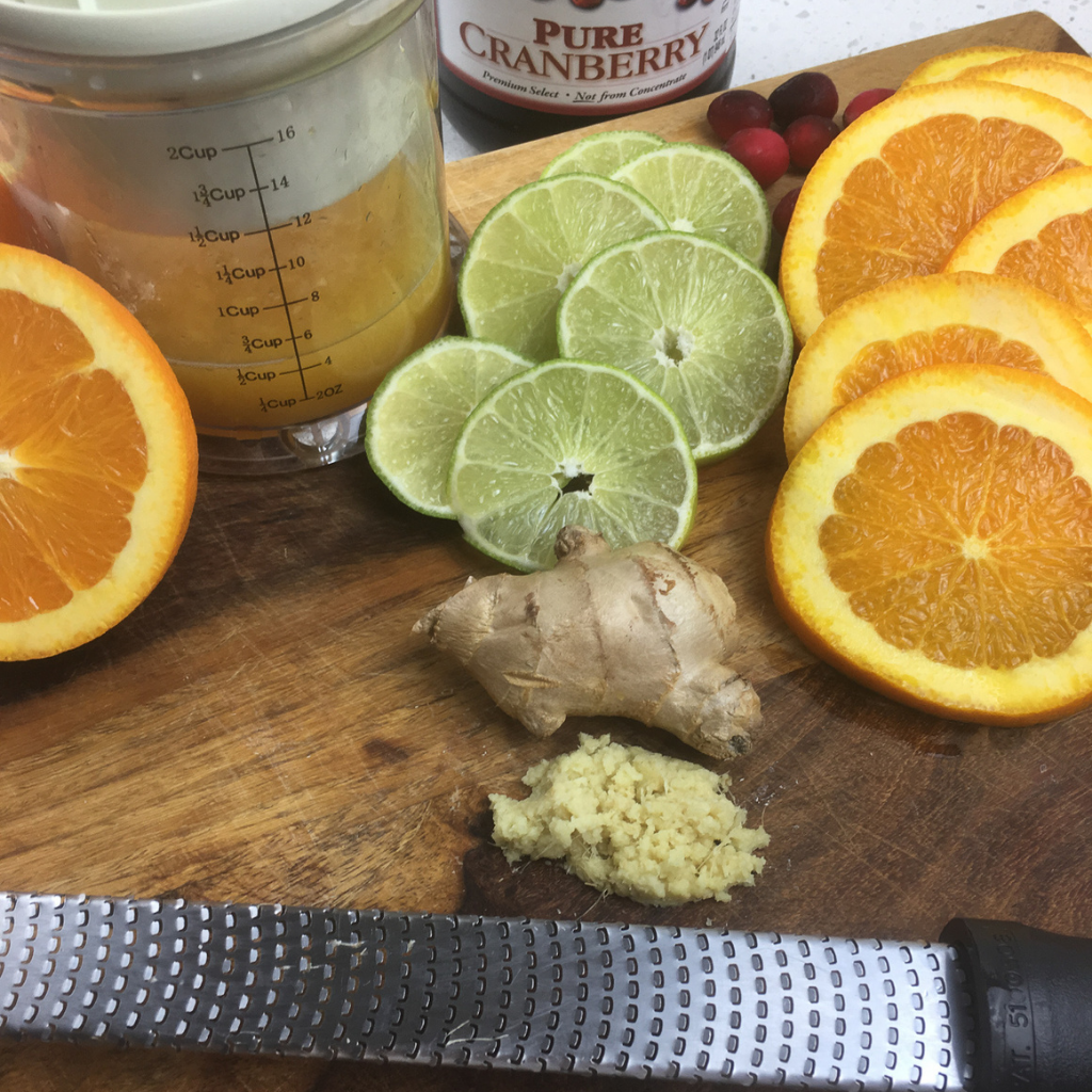 ingredients for cranberry orange punch on a chopping board with a grater